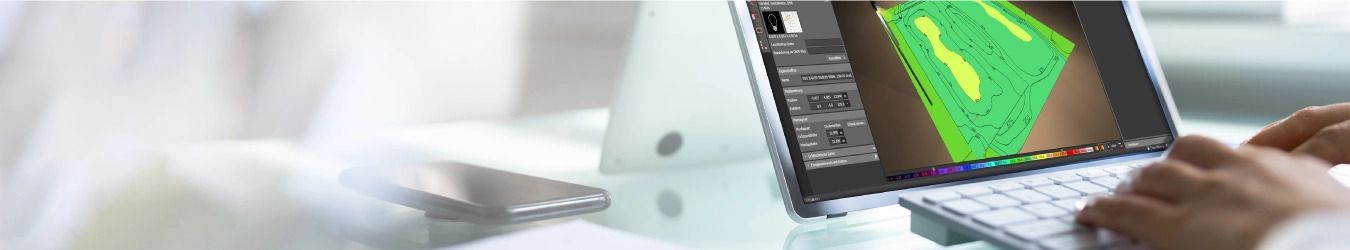 Ein Laptop zeigt ein topografisches Design auf dem Bildschirm. Eine Person tippt auf der Tastatur. Im Hintergrund befinden sich ein Smartphone und ein verschwommener B&uuml;roraum.